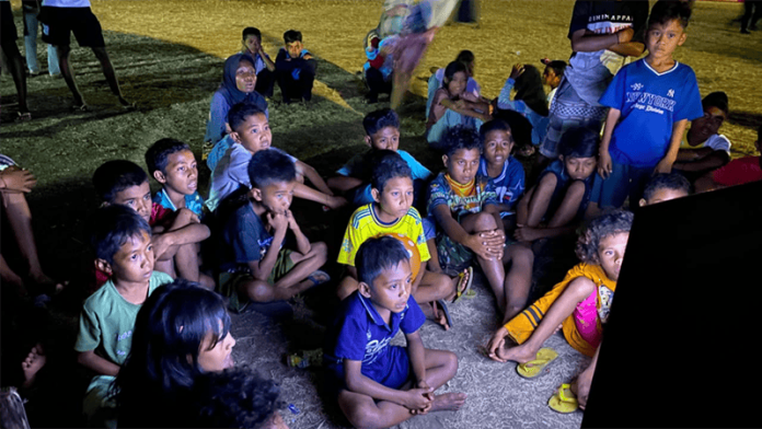 Anak-anak tampak antusias, tertawa, dan menikmati tayangan bersama